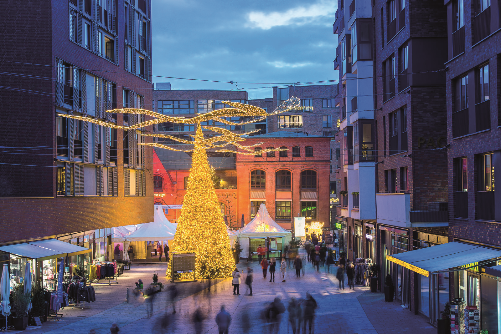Das Bild zeigt den Überseeboulevard zur Weihnachtszeit mit Ständen, Weihnachtsbaum und leuchtender Deko